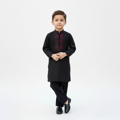 Young boy wearing a black traditional outfit with a white background
