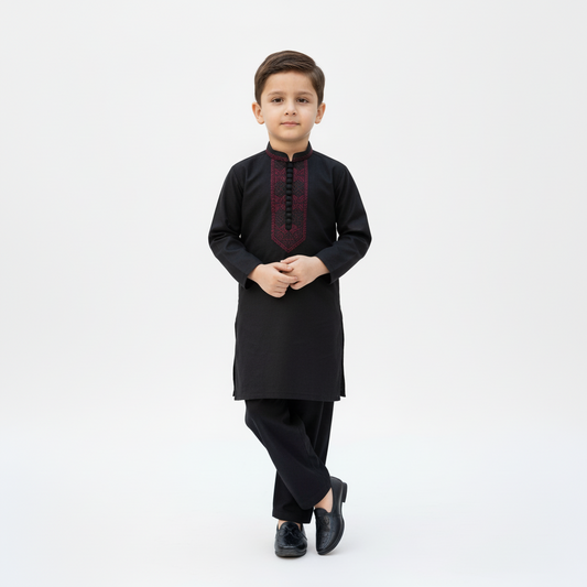 Young boy wearing a black traditional outfit with a white background