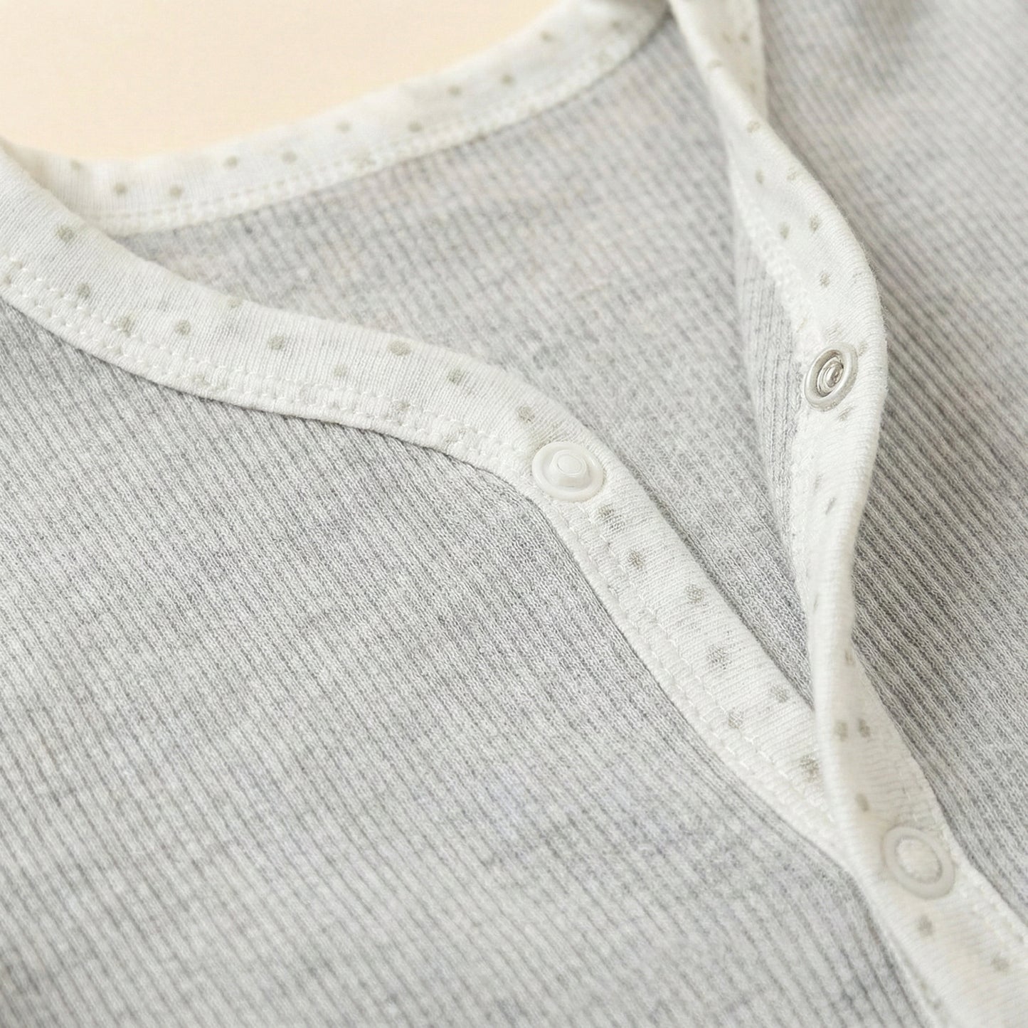 Close-up of a baby outfit with a textured gray pattern and white trim.