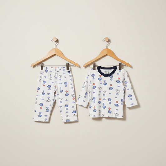 Children's pajama set with long-sleeve shirt and pants on hangers against a beige background