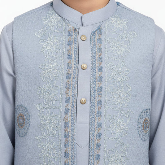Young boy wearing a light blue traditional outfit on a white background