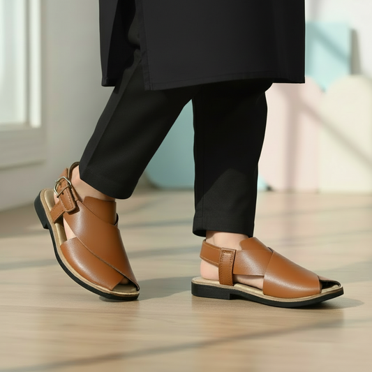 Brown leather sandals worn with beige pants on a wooden floor.