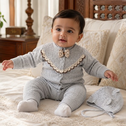 Baby wearing gray cable knit romper set in a warm Pakistani home setting